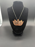 Necklace with a copper lotus flower pendant on a black mannequin bust.