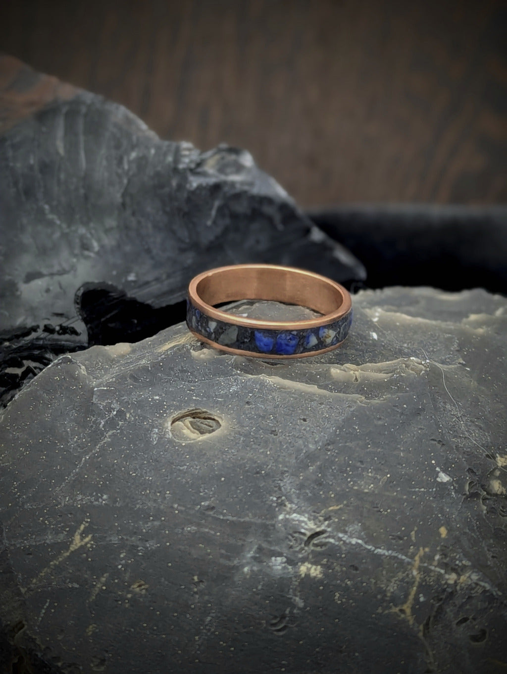 Copper ring with blue lapis lazuli inlay on a dark stone surface
