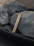 A solid copper bar with green malachite inlay running along the long side. The pendant is set against obsidian rocks and a velvet surface.