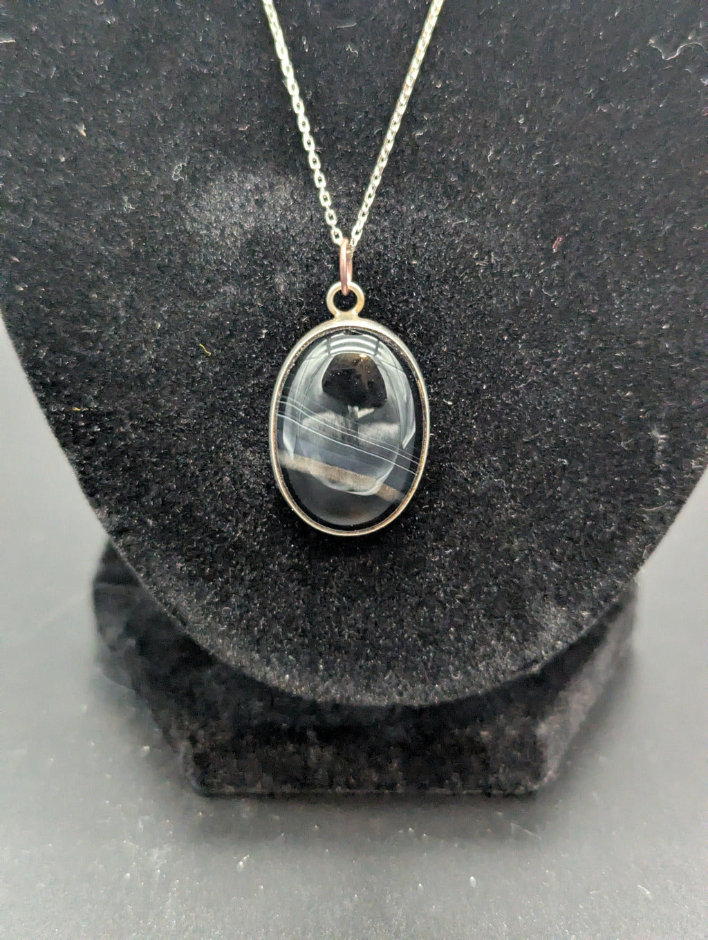 Necklace with a pendant  and a black striped stone cabochon on a black stand