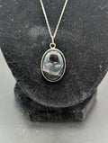 Necklace with a pendant  and a black striped stone cabochon on a black stand