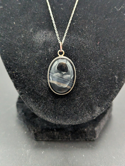 Necklace with a pendant  and a black striped stone cabochon on a black stand