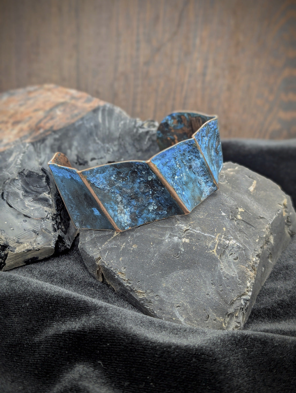 Copper cuff featuring a rough blue patina and high lines of polished copper.
