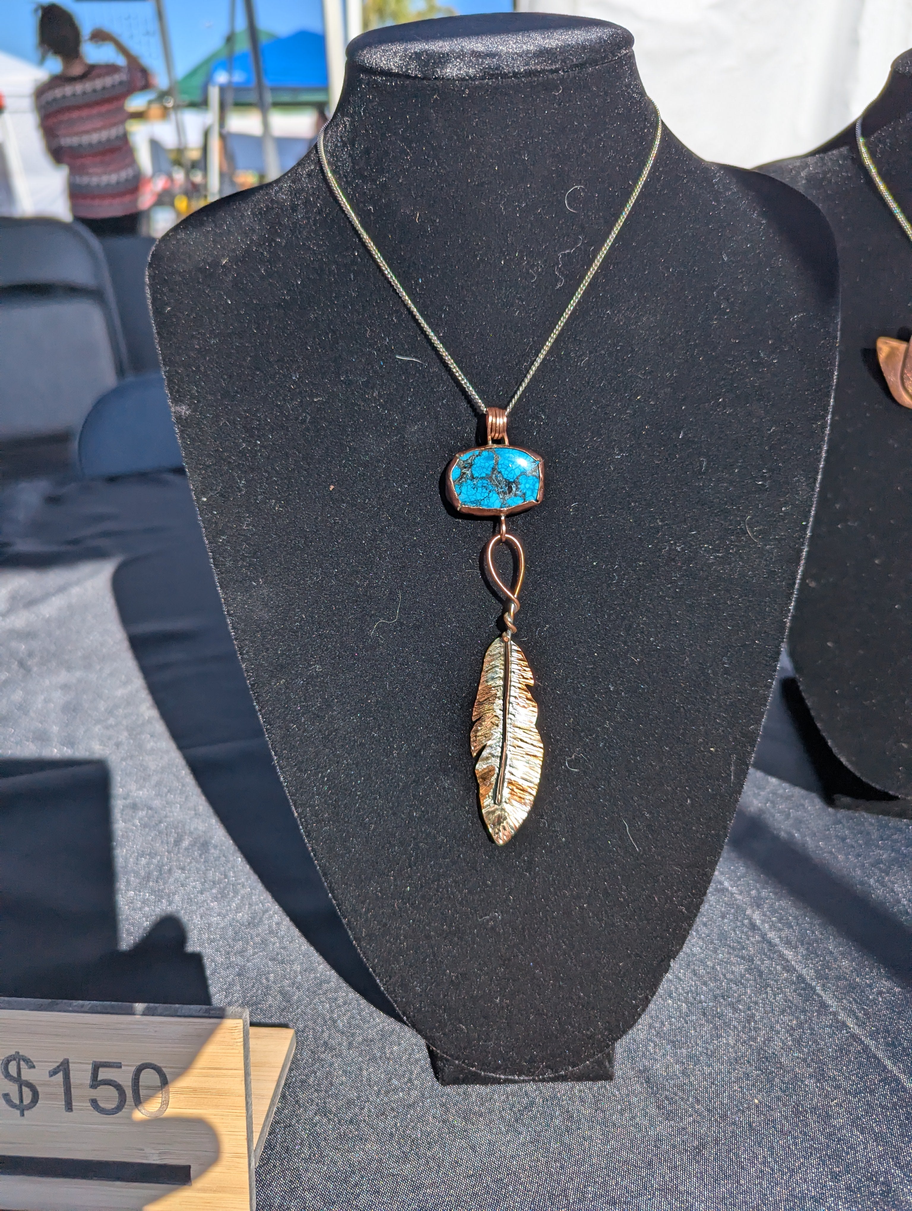 Necklace pendant of a handmade copper turquoise setting and feather. The feather has had several effects applied to it to give it a burnt but shiny look.
